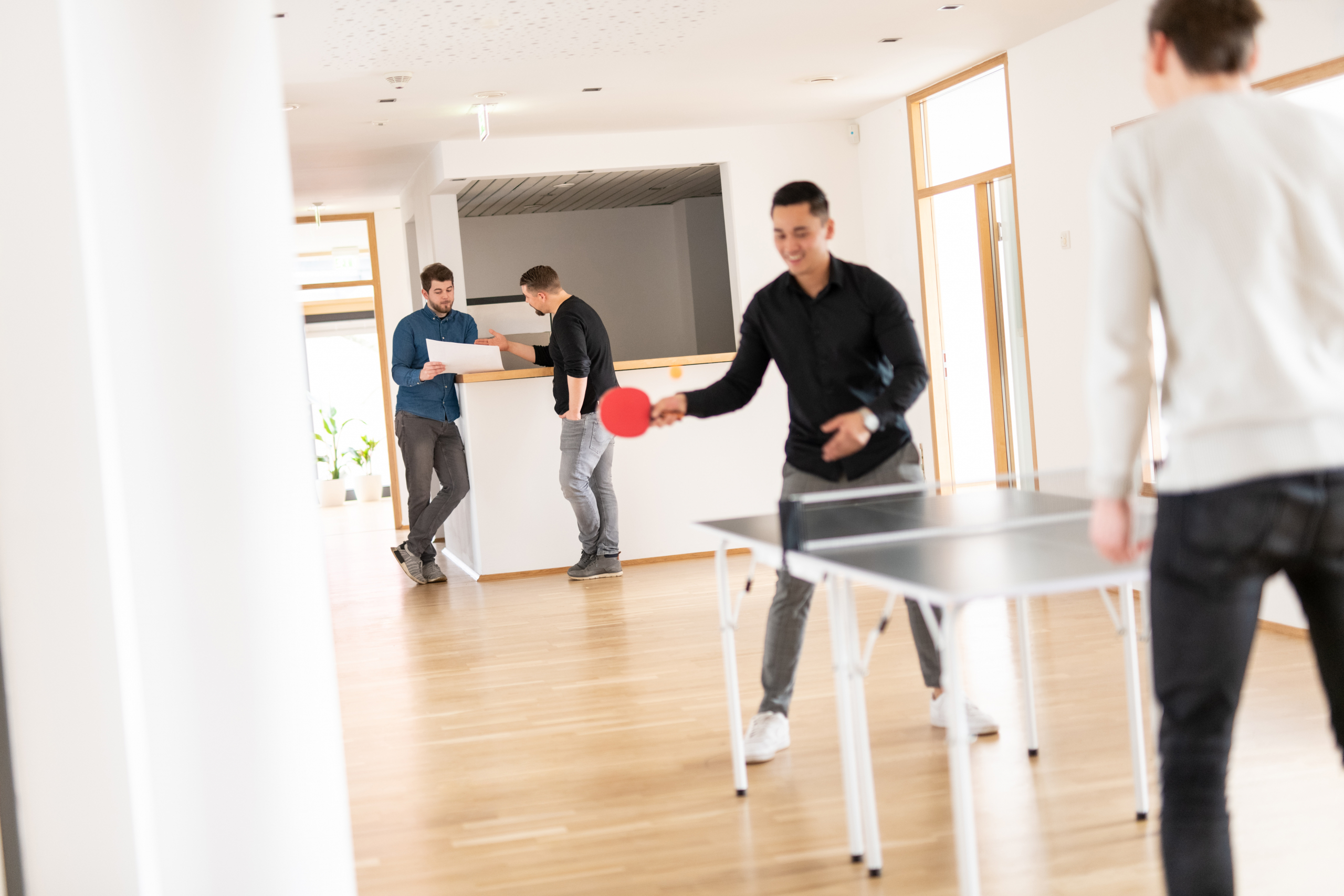 Mitarbeiter im Pausenraum beim Tischtennisspielen